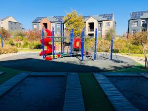 einen Spielplatz in einem Park vor einigen Gebäuden in der Unterkunft 13 Elizabeth Place - Beautiful 2 bedroom unit next to Kyalami Racetrack with free WiFi - swimming pool gym and restaurant - Perfect for a small family in Midrand Waterfall in Midrand