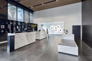 a lobby with a counter with a person walking in the background at Vibe Hotel Melbourne Docklands in Melbourne