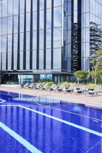 a hotel swimming pool with chairs and a building at Vibe Hotel Melbourne Docklands in Melbourne