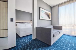 a room with a bed and a couch and a window at Vibe Hotel Melbourne Docklands in Melbourne