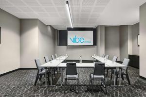 a conference room with tables and chairs and a screen at Vibe Hotel Melbourne Docklands in Melbourne