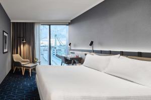 a hotel room with a large white bed and a desk at Vibe Hotel Melbourne Docklands in Melbourne
