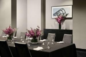 a table with purple flowers in vases on it at Vibe Hotel Melbourne Docklands in Melbourne
