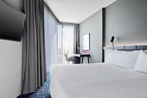 a hotel room with a bed and a desk at Vibe Hotel Melbourne Docklands in Melbourne
