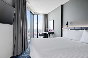 a hotel room with a bed and a large window at Vibe Hotel Melbourne Docklands in Melbourne