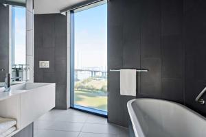 a bathroom with a tub and a sink and a window at Vibe Hotel Melbourne Docklands in Melbourne