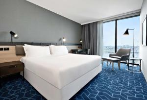 a hotel room with a large bed and a desk at Vibe Hotel Melbourne Docklands in Melbourne