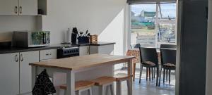 a kitchen with a wooden table and some chairs at Klipvis at Duykereiland in St Helena Bay