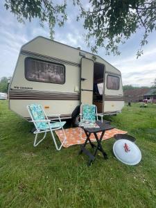 two chairs and a table in front of a caravan at Vintage caravan in old orchard at farm Huize Blokland in Hem