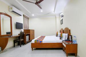 a bedroom with a bed and a desk and a mirror at FabHotel CS Jalandhar in Jalandhar