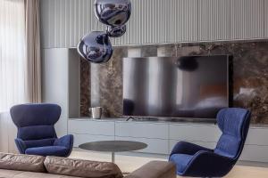 维尔纽斯Luxury Smart Home Apartment in Vilnius Old Town, Sleep on Hästens的客厅配有蓝色椅子和电视