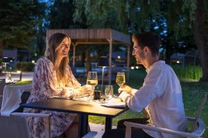 a man and woman sitting at a table with wine glasses at Das Parkhotel - Südtirols nördlichster Punkt in Bad Wörishofen
