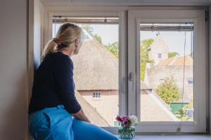 a woman sitting on a window sill looking outside at La Fornaccia in Anloo
