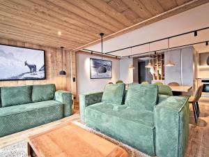un soggiorno con divani verdi e un tavolo di Chalet familial 12 pers avec jacuzzi et ski-in/ski-out - FR-1-613B-40 a Les Bruyères