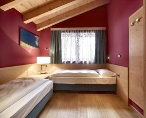 a bedroom with two beds and a window at Color Home Suite Apartments in Predazzo