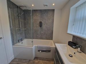 a bathroom with a shower and a tub and a sink at Homely 3 Bedroom home near town centre & only 1 mile from Bike Park Wales in Merthyr Tydfil +11 photos