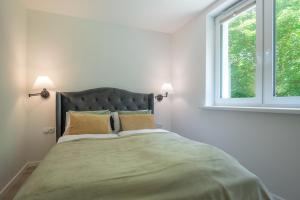 a bedroom with a large bed with two windows at VacationClub - Podgórzyńska 6A Apartament 5 in Jelenia Góra