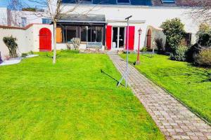 a house with a red door and a grass yard at Charming family home in Couëron in Couëron