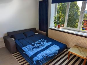 a bedroom with a bed with a blue comforter and a window at Lost & Found 3 - with 4 bikes in Pāvilosta