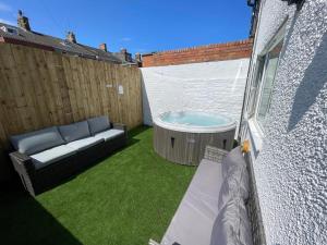 ein kleiner Hinterhof mit Whirlpool und Sofa in der Unterkunft Marine Cottage 2 - With Private Hot Tub in Newbiggin-by-the-Sea