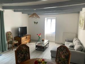 a living room with a couch and a tv at Gîte le temps de vivre in Pressac