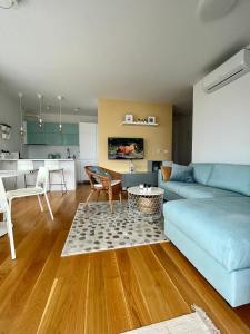 a living room with a blue couch and a kitchen at EllaSea - Beachside in Zaboric