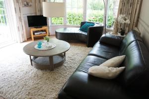 a living room with a black leather couch and a table at Kustverhuur, Groede Paarlhof 19 in Groede