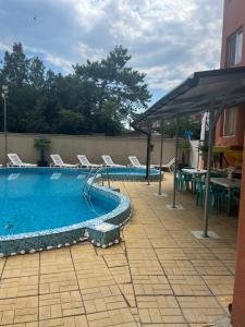 a swimming pool with chairs and a table next to a building at Къща Нанси in Sunny Beach