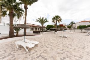 a patio with chairs and umbrellas and palm trees at 1 BR Condo Chapelas Costa del Silencio AC Pool WIFI in Arona