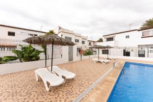 a pool with umbrellas and lounge chairs next to a pool at 1 BR Condo Chapelas Costa del Silencio AC Pool WIFI in Arona