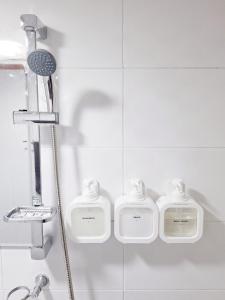 a bathroom with three soap dispensers in a shower at Hue stay 2 in Seoul