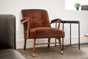 a brown chair sitting next to a glass table at Huge Duplex in Great Location in Heaton