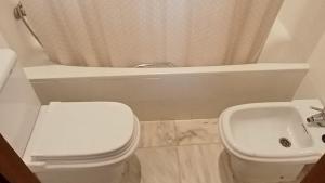 ein Badezimmer mit einer weißen Toilette und einem Waschbecken in der Unterkunft Apartamentos Jasmund - Bungalow 87 in San Fernando