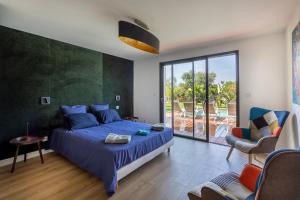 une chambre avec un lit bleu et une porte coulissante en verre dans l'établissement Villa de la Madrague Vue Mer à 200m de la Plage sur La Presqu' île de Giens Sea and Mountain Pleasure, à Hyères 130 autres photos
