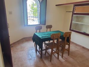 a dining room with a green table and chairs at PAUL's COTTAGE in Kallidaikurichchi