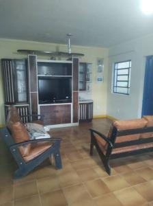 a living room with two chairs and a flat screen tv at Exclusivo Haras Marilu! in Atibaia