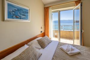 a bedroom with a bed with a view of the ocean at Hotel Dobrovit in Baška