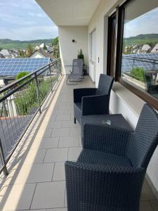 a balcony with chairs and a view of solar panels at Ferienwohnung im Kirchberg in Lieser