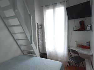 a bedroom with a bed and a staircase next to a window at Chambre familiale in Cachan