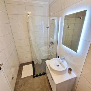 a white bathroom with a sink and a shower at Apartman BOSS Lux in Trebinje