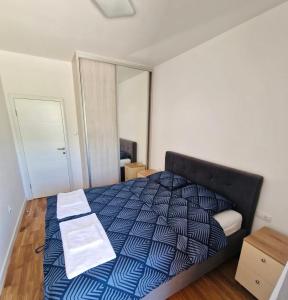 a bedroom with a bed with a blue and white comforter at Apartman BOSS Lux in Trebinje