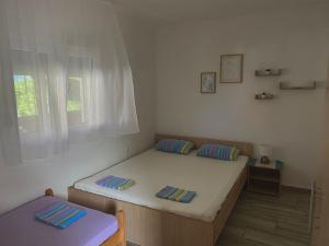 a small bedroom with a bed and a window at Vila Andja, Apartmani i Sobe in Krašići