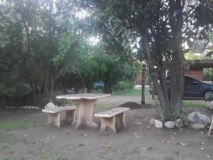 une table de pique-nique et deux bancs sous un arbre dans l'établissement Cabañas La Fiaca, à Los Manantiales 1 autre photo