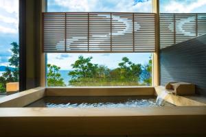 a bathtub with a large window with a view of the ocean at 間人温泉 炭平 in Kyotango