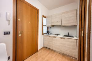 a small kitchen with wooden cabinets and a door at Emilia Studios in Modena +9 photos