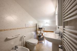 a white bathroom with a toilet and a sink at Emilia Studios in Modena
