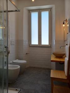 een badkamer met 2 wastafels, een toilet en een raam bij Holiday Homes Villetta Blu in Nettuno