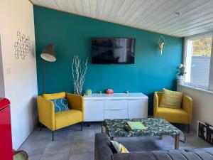 un salon avec deux chaises jaunes et un mur bleu dans l'établissement Lodge des pins au coeur de la forêt d'Olonne, à Olonne-sur-Mer