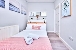 zwei Betten in einem kleinen Schlafzimmer mit einer rosa Decke in der Unterkunft Princess Red 1 - Portrush by the Sea in Portrush