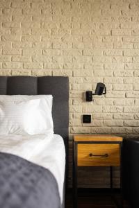 a bedroom with a bed and a nightstand next to a brick wall at Różana Loft - Old Town in Kraków
